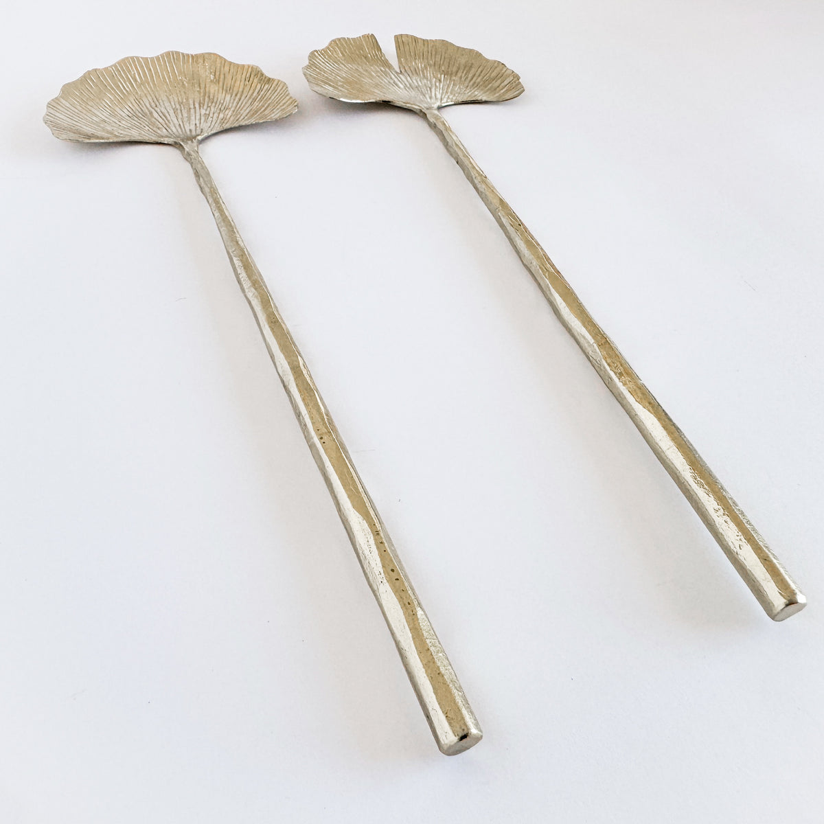 M. By Design - Curated tabletop essentials. Two decorative spoons with leaf-like ends on a white background