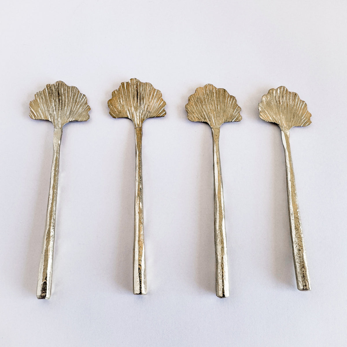 M. By Design - Curated tabletop essentials. Four gold shell-shaped spoons on a white background