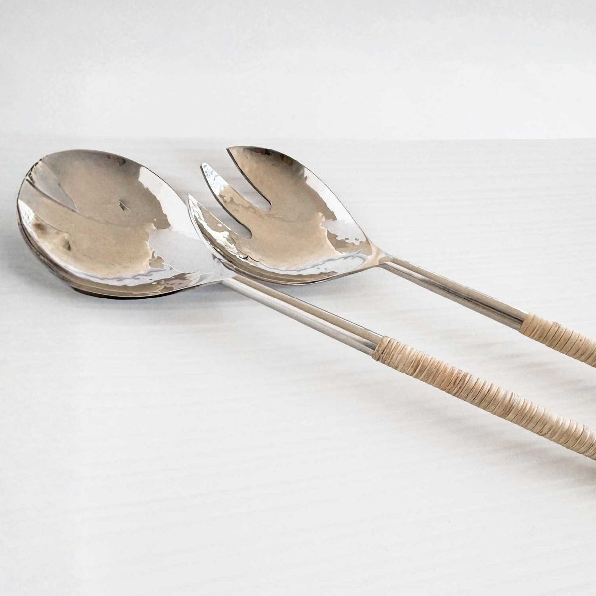 M. By Design - Curated tabletop essentials. Silver salad servers with woven handles on a light gray background