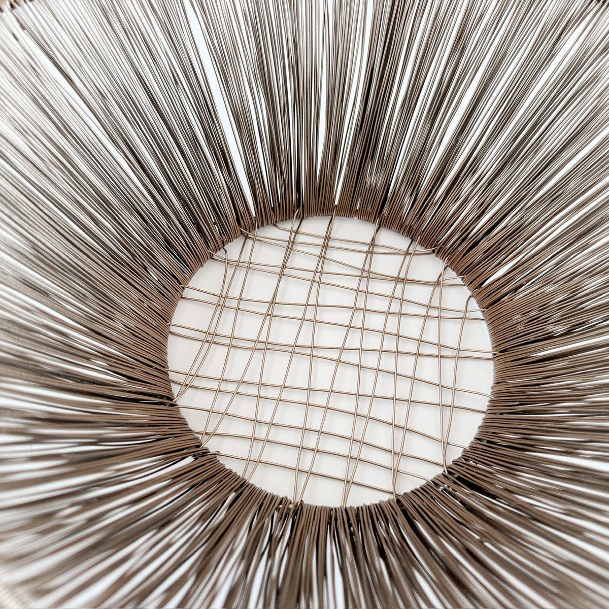 M. By Design - Curated tabletop essentials. Close-up of a woven circular object with a grid pattern in the center.